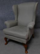 A Georgian style upholstered wing back armchair on cabriole supports. H.99cm