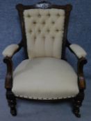 A late Victorian carved walnut armchair on turned tapering supports terminating in ceramic