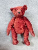 A 20th century straw filled red plush humpback teddy bear with jointed limbs. H47cm.