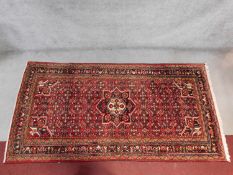 A Hosseinabad rug with central pendant medallion on a rouge field with repeating floral motifs