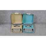 Two vintage typewriters in carrying cases. One pale blue Smith Corona Corsair and a cream Smith