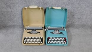 Two vintage typewriters in carrying cases. One pale blue Smith Corona Corsair and a cream Smith