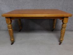 A pine dining table on turned tapering supports terminating in ceramic casters. H.73 W.137 D.94cm