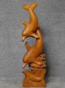 A carved sculpture of a family of dolphins surfing in the waves. H.102cm