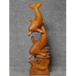 A carved sculpture of a family of dolphins surfing in the waves. H.102cm