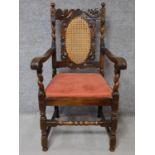 A Jacobian style oak armchair with carved and caned back on stretchered supports. H.109cm
