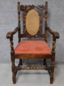 A Jacobian style oak armchair with carved and caned back on stretchered supports. H.109cm