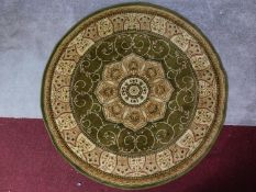 A circular Eastern rug with central pendant medallion on a green and ivory field 150x150cm