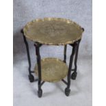 A Chinese hardwood folding occasional table with scalloped edged brass trays with an engraved