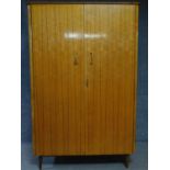 A 1960's vintage satin birch fitted wardrobe with asymmetric mahogany strung detail on tapering