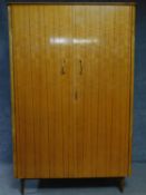 A 1960's vintage satin birch fitted wardrobe with asymmetric mahogany strung detail on tapering