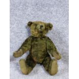 A 20th century green plush straw filled humpback teddy bear with jointed limbs.. H32cm.