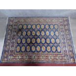 A Bokhara rug with repeating elephant pad motifs on a sapphire field surrounded by repeating multi