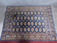 A Bokhara rug with repeating elephant pad motifs on a sapphire field surrounded by repeating multi