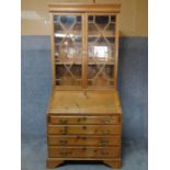 An antique country style pitch pine bureau bookcase with astragal glazed doors above fall front