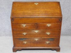 A Georgian oak bureau with fall front revealing a fitted interior with slide revealing hidden well