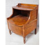 A Georgian mahogany night table with folding shelf and panel enclosing compartment on turned