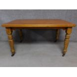 A pine dining table on turned tapering supports terminating in ceramic casters. H.73 W.137 D.94cm