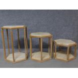 A limed oak framed set of three marble topped graduating occasional tables with marble bases. H.62