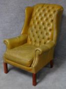 A Georgian style leather upholstered button back wing armchair on square mahogany supports. H.100cm