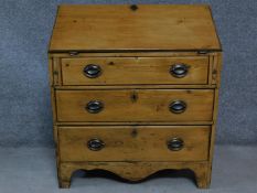 A Georgian pine bureau the fall front revealing fitted interior above three graduating drawers on