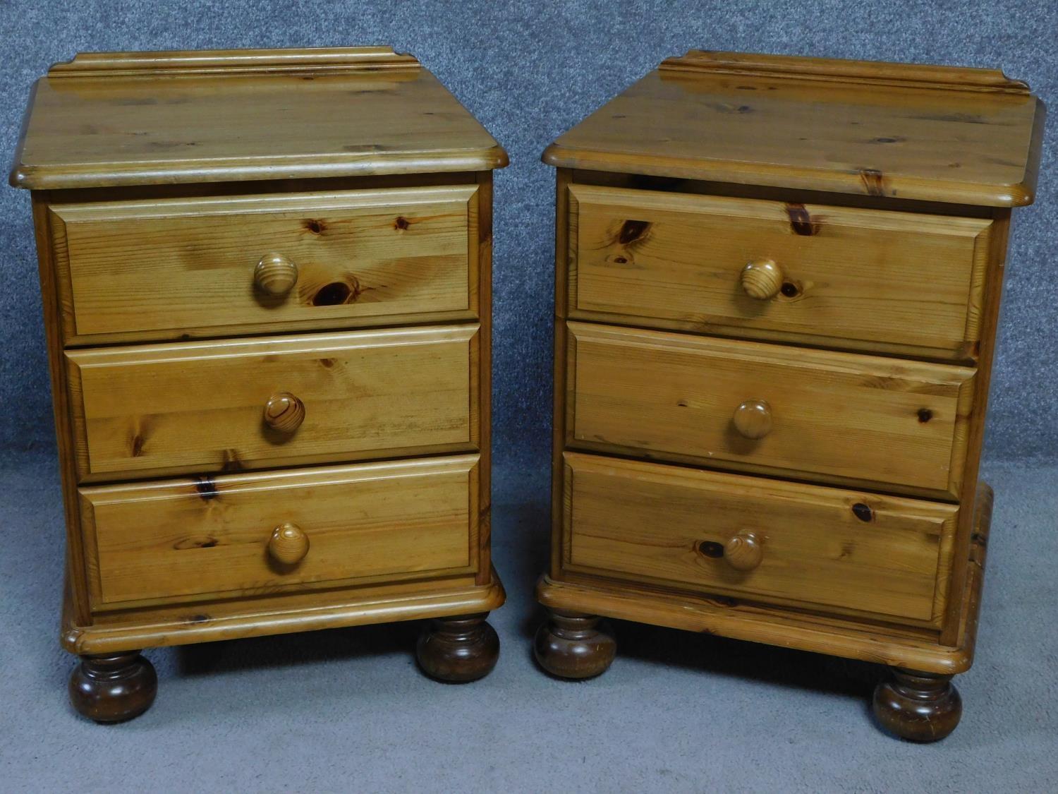 A pair of contemporary pine bedside chests with three drawers on casters, by English maker Victoria.