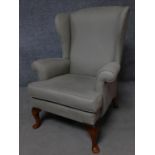A Georgian style upholstered wing back armchair on cabriole supports. H.99cm