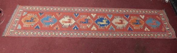 A Kazak style runner, repeating reindeer motifs on a terracotta field within geometric border