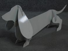 A metal painted sculpture of a sausage dog by British artist Peter Clark. 32x80cm