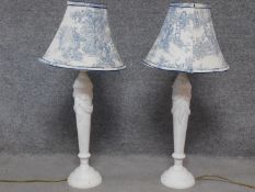 A pair of vintage white carved table lamps with blue and white shades. Bases have relief bow and