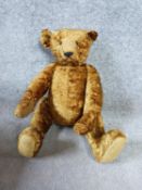 A 20th century straw filled golden plush humpback teddy bear with jointed limbs.. H51cm.