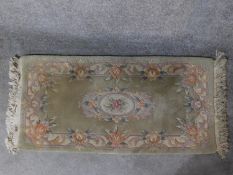 A Chinese rug with central floral medallion set on a pastel field within floral borders 144x63cm