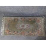 A Chinese rug with central floral medallion set on a pastel field within floral borders 144x63cm