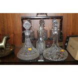 A THREE BOTTLE TANTALUS TOGETHER WITH THREE CUT GLASS DECANTERS