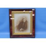 A FRAMED AND GLAZED PORTRAIT OF AN ELDERLY LADY SAT IN A ROCKING CHAIR