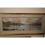 A GILT FRAMED AND GLAZED WATERCOLOUR DEPICTING A SAILBOAT IN A MOUNTAINOUS LAKE SCENE INITIALLED