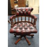 A MODERN OXBLOOD RED SWIVEL OFFICE ARMCHAIR