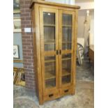 A MODERN SOLID OAK GLAZED BOOKCASE WITH DRAWERS BELOW H-190 W-89 CM