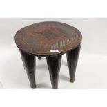 AN EARLY 20TH CENTURY NUPE CARVED WOODEN STOOL, with a chip carved top over seven tapering legs,