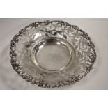 A PIERCED WHITE METAL FOOTED DISH, decorated with a fruiting vine design, Dia 17.75 cm