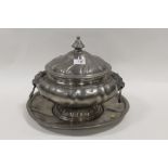 A LARGE PEWTER LIDDED TWIN HANDLED TUREEN AND STAND WITH LION MASK HANDLES