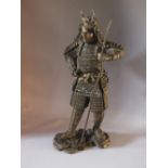 A LARGE BRONZE SAMURAI HOLDING A LOOSE SPEAR, standing on a rocky outcrop, H 47 cm