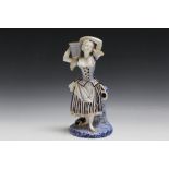 A ROYAL WORCESTER BLUE AND WHITE FIGURE OF A LADY CARRYING A BASKET, H 27 cm