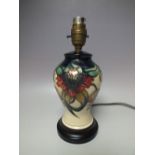 A MOORCROFT 'ANNA LILY' PATTERN SMALL TABLE LAMP, raised on a circular wooden base, tubeline