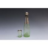 A NOVELTY CONTINENTAL SILVER MOUNTED MINIATURE CHAMPAGNE BOTTLE AND MATCHING SHOT CUP, bottle H 18