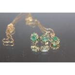 AN EMERALD AND DIAMOND CLUSTER EARRING AND PENDANT SET, the central emerald of the pendant being