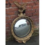 A REGENCY STYLE CONVEX WALL MIRROR, with an eagle crest over a ball mounted cavetto moulded frame,