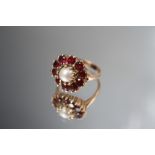 A HALLMARKED 9CT GOLD PEARL AND GEMSET DRESS RING, the single pearl surrounded by ten garnet type