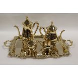 A GILDED METAL FOUR PIECE TEA SERVICE ON MATCHING TWIN HANDLED SERVING TRAY
