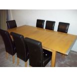 A HARDWOOD EXTENDING DINING TABLE AND SIX LEATHER EFFECT PADDED CHAIRS